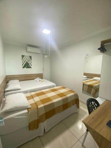 a bedroom with two beds and a table in it at Hotel Trevo Caruaru in Caruaru