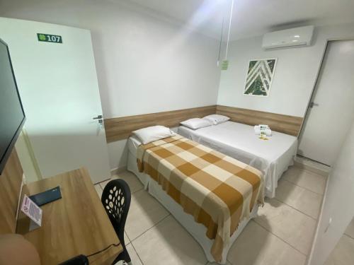 a small room with two beds and a table at Hotel Trevo Caruaru in Caruaru