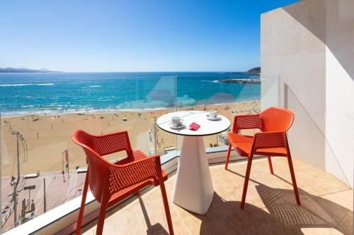 a dining room table and chairs at the beach at Hotel Cristina by Tigotan Las Palmas - Adults Only in Las Palmas de Gran Canaria
