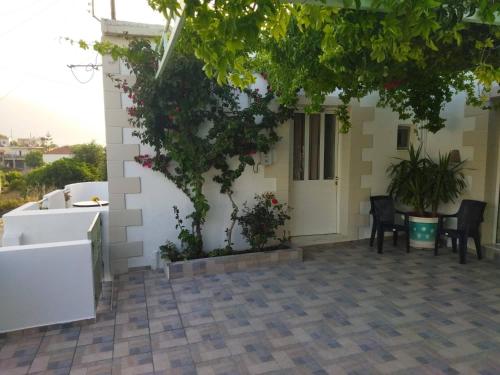 a white house with a table and chairs in front of it at Yannis apartments in Georgioupolis