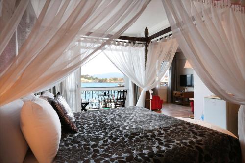 a bedroom with a bed with white curtains and a window at URLA PERA HOTEL in Urla