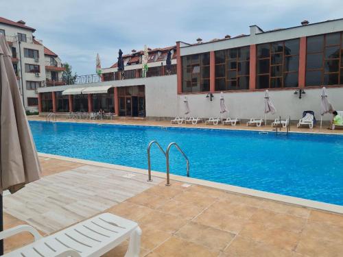 a swimming pool next to a building with a hotel at Famagusta Antoniya in Aheloy