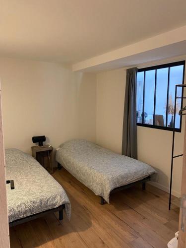 une chambre avec deux lits et une grande fenêtre dans l'établissement Appartement 3 étoiles tout confort et spacieux en campagne bourguignonne, à Mancey