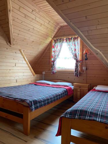 two beds in a log cabin with a window at Domki Chatka U Staszka in Małe Ciche