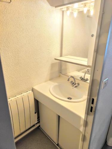 une salle de bain blanche avec un lavabo et un miroir dans l'établissement Petit coin de paradis en plein centre de Barèges, à Barèges