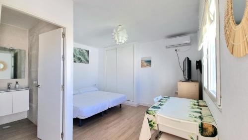 a white bedroom with a bed and a mirror at Habitación privada con baño y jardín privado in Chiclana de la Frontera