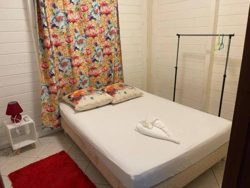 a bed with two pillows and a shower curtain at Bas de villa couleuvre in Deshaies