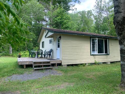 a cabin with a wooden deck and chairs on it at Colonial Bay Motel and Cottages in Huntsville