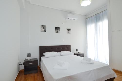 a white bedroom with a large bed and a window at A spacious minimal apatment at Chalandri in Athens