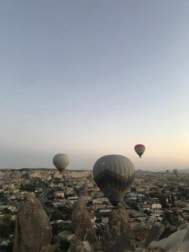 three hot air balloons flying over a city at Grand Uchisar Hotel in Uchisar