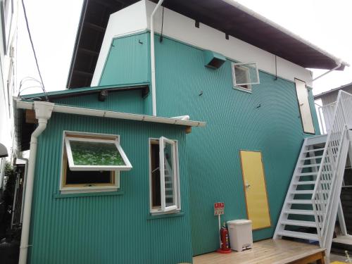 a green house with a white door and stairs at Wataya Inn in Fujisawa