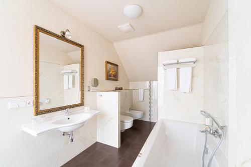 a bathroom with a sink and a tub and a toilet at Spa Hotel Vita in České Budějovice
