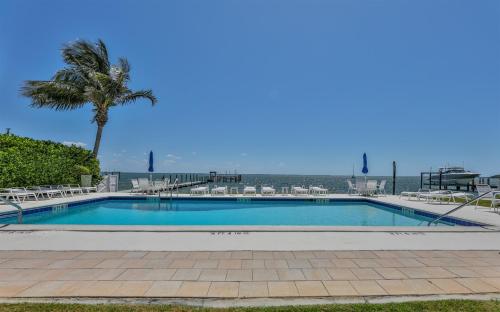 a swimming pool with a palm tree and chairs at Captiva Hide A Way 2B in Captiva