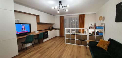 uma sala de estar com um sofá e uma cozinha com uma televisão em Hara House em Cluj-Napoca