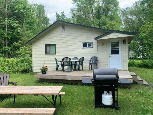 a house with a deck with a table and chairs at Colonial Bay Motel and Cottages in Huntsville