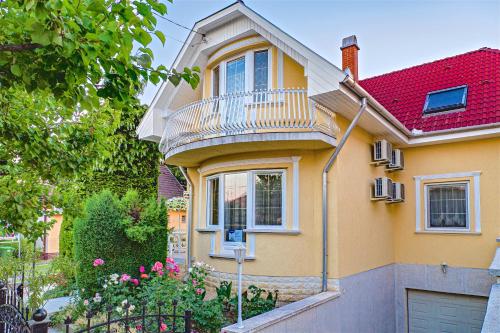 een geel huis met een balkon erboven bij CSONTOS VENDÉGHÁZ in Hajdúszoboszló