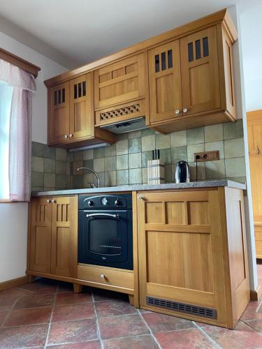 a kitchen with wooden cabinets and a black oven at Penzion Kovárna in Bukvice