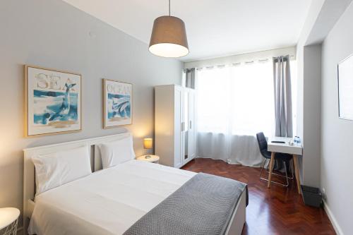een slaapkamer met een bed, een bureau en een raam bij Lolla's City House in Porto