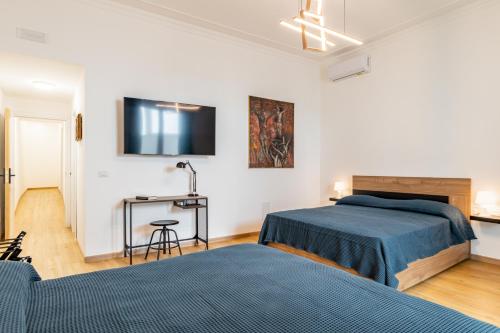 Un dormitorio con dos camas y un televisor en la pared. en Aurora Rooms, en Catania