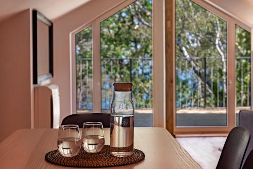 a bottle of water and two glasses on a table at Apartamenty Na Klifie Przystań 18 Chłapowo in Władysławowo