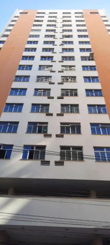 a tall white building with blue windows at Vem pra cá! Localização Privilegiada! in Guarapari
