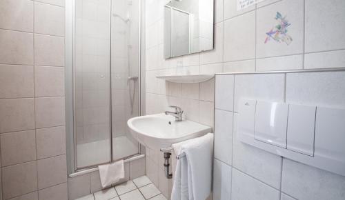 a white bathroom with a sink and a shower at Hotel Schwung in Bocholt