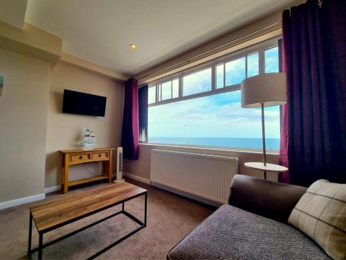 a living room with a couch and a large window at The Ramleh in Scarborough