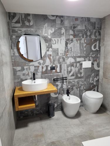 a bathroom with a sink and a mirror and a toilet at Urban Rooms Porto Cesareo in Porto Cesareo