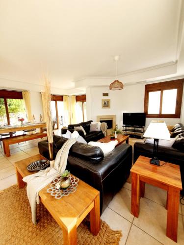 Impresionante villa PISCINA JARDÍN ALTAONA GOLF في مورسية: غرفة معيشة مع أريكة جلدية سوداء وطاولات