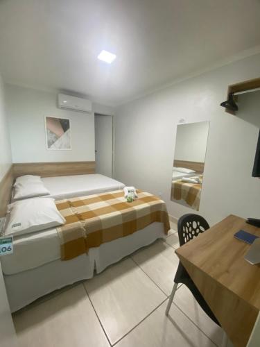 a bedroom with a large bed and a table at Hotel Trevo Caruaru in Caruaru