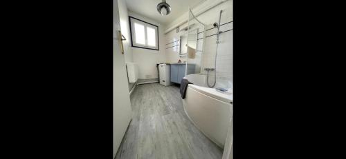 een badkamer met een bad, een toilet en een wastafel bij Le Panoramique. Appartement vue mer. in Saint-Valéry-en-Caux