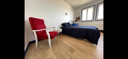 een slaapkamer met een bed en een rode stoel bij Le Panoramique. Appartement vue mer. in Saint-Valéry-en-Caux
