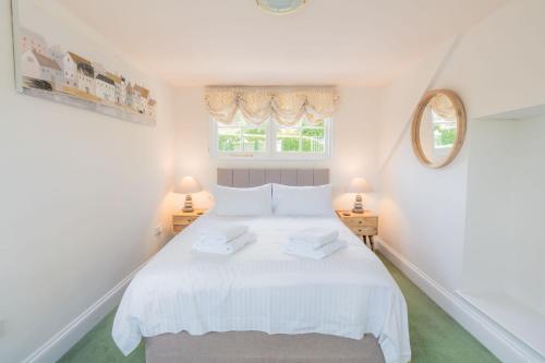 a white bedroom with a white bed with two lamps at The Old Coach House Salcombe in Salcombe