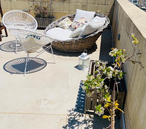 a patio with a basket and chairs and plants at Casa Cara in Birgu