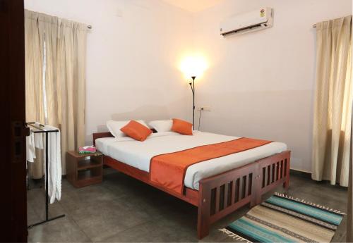 a bedroom with a large bed with orange pillows at Monsoon Apartments in Kannur