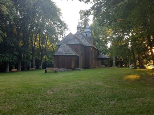 un gran edificio de madera en un campo con un banco en Cottage Room- Agroturystyka, en Strzegowo-Osada