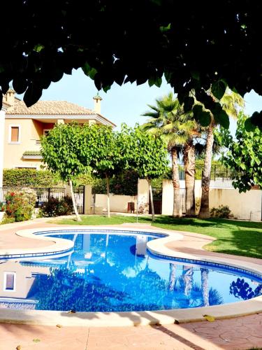una piscina en un patio con árboles y una casa en Impresionante villa PISCINA JARDÍN ALTAONA GOLF, en Murcia