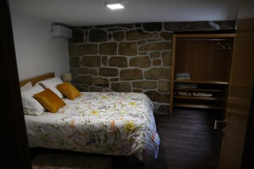 a bedroom with a bed and a stone wall at Casa do Eirô in Pinheiro