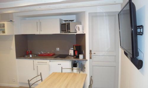 a kitchen with white cabinets and a table and a tv at Gite de l'Ancien Moulin in Valmont
