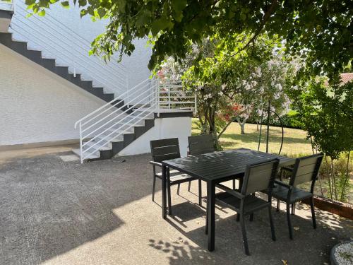 a black table and chairs in a yard with a staircase at Valica Gardens in Savudrija