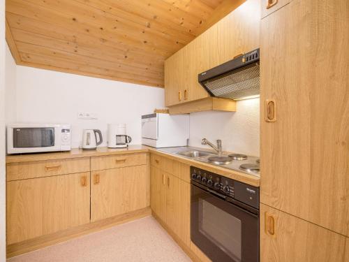 a kitchen with wooden cabinets and a stove and microwave at Apartment Kraxner in Sölden