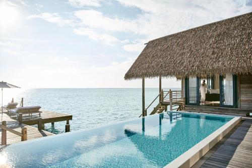 a swimming pool in front of a house on the ocean at COMO Cocoa Island - Partner Travels FREE for 7 Nights or More in Male City