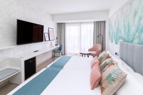 a hotel room with a large bed and a television at Hotel Cristina by Tigotan Las Palmas - Adults Only in Las Palmas de Gran Canaria