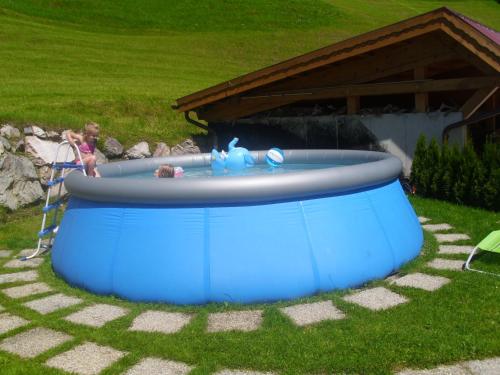 a child playing in a pool in a yard at Untersteinhof in Forstau