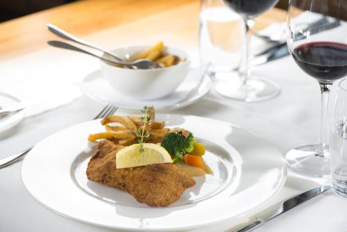 a white plate with fish and vegetables on a table at Anker Hotel Restaurant in Teufen