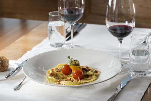 a plate of food on a table with wine glasses at Anker Hotel Restaurant in Teufen