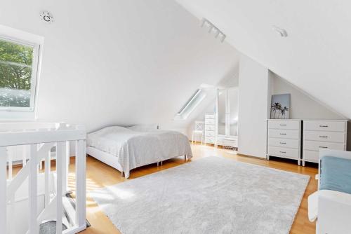 a white bedroom with a bed and a white rug at Am Seehof in Sierksdorf