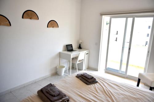 ein Schlafzimmer mit einem Bett und einem Schreibtisch mit einem Laptop in der Unterkunft Casa Franki - Stylish and large beach apartment in Algarve in Carvoeiro