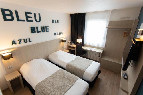 a hotel room with two beds and a desk at Hôtel Relais d'Étretat in Bolbec
