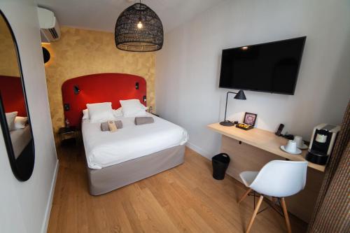a bedroom with a bed with a red headboard and a television at Hotel Kanaï in Lille